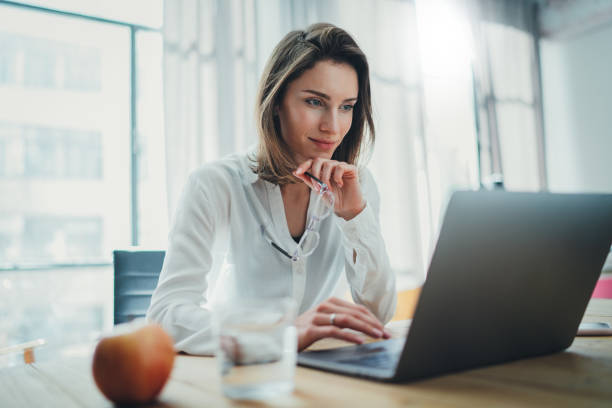 Confident businesswoman working on laptop at her workplace at modern office.Blurred background